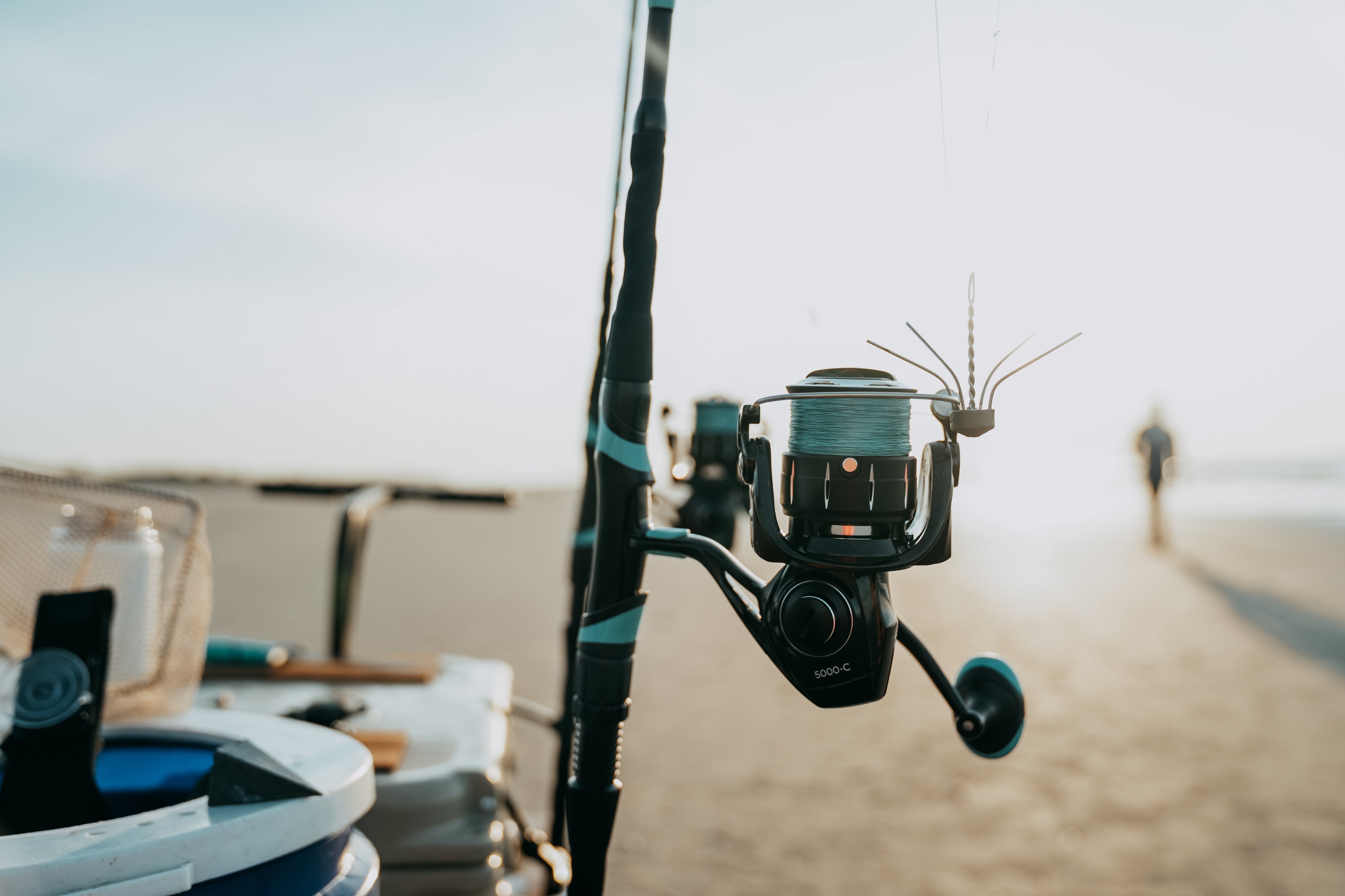 a photo shows a surf fishing rod sitting in a beach fishing cart on the beach