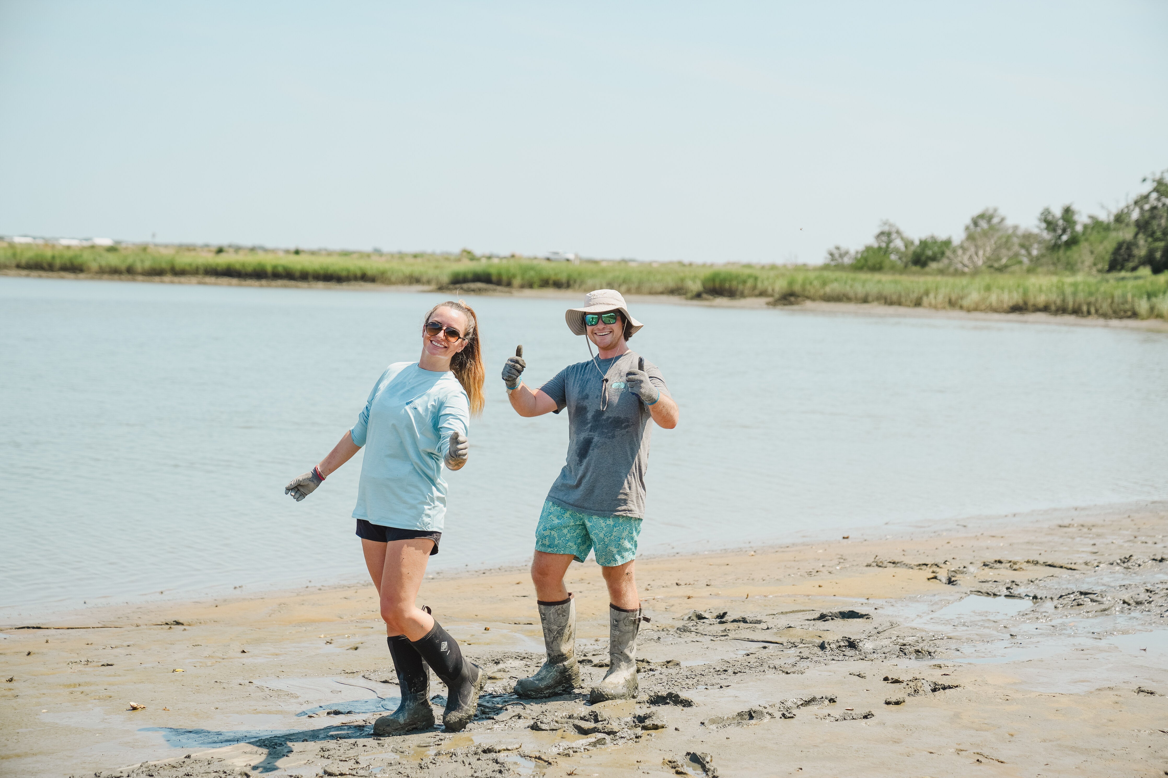 Two people are celebrating conservation; they are standing in the mud where they are working.