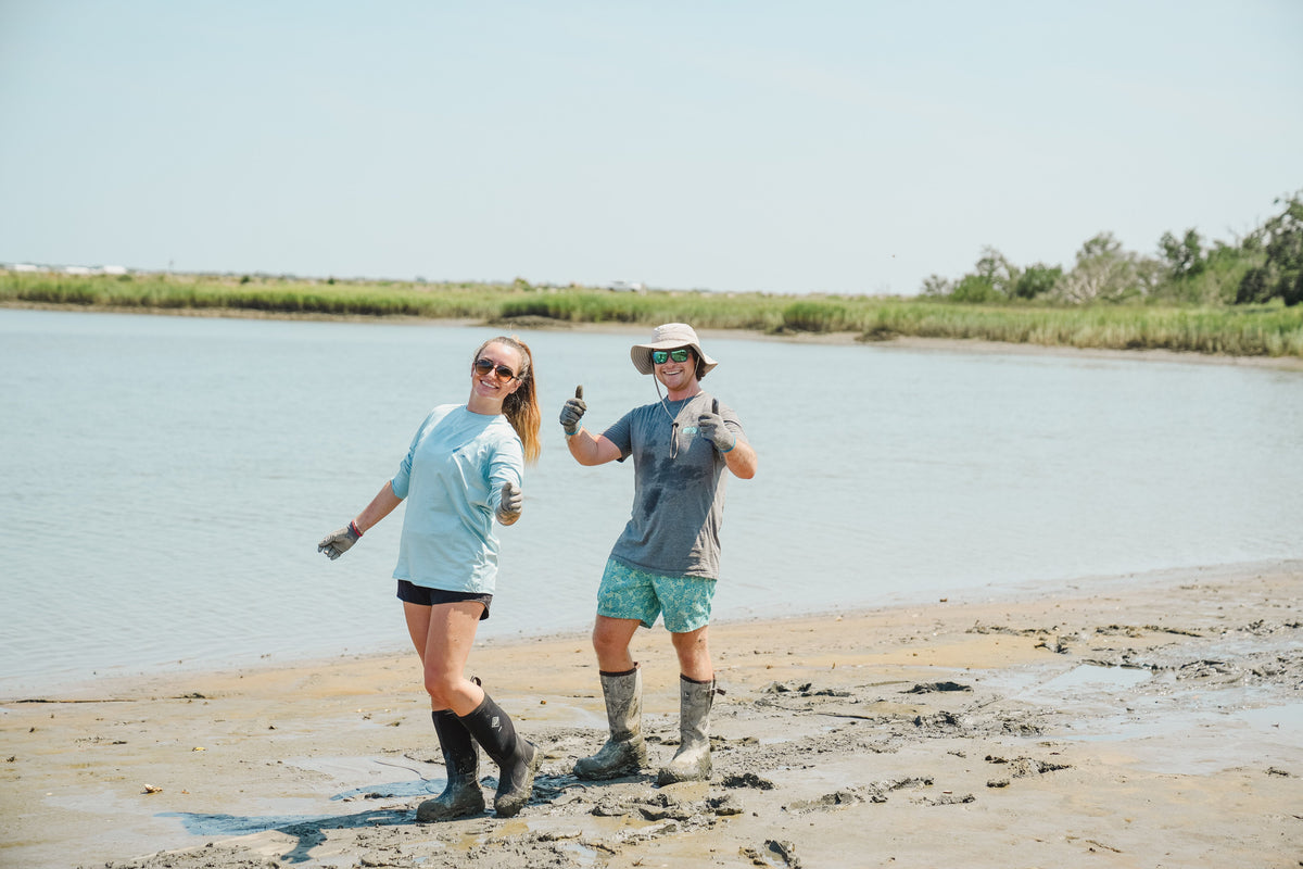 Two people are celebrating conservation; they are standing in the mud where they are working.