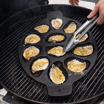 a cowboy butter grilled oyster is being held up to the camera, it looks delicious