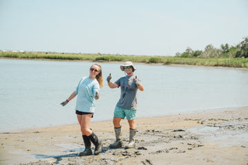 Two people are celebrating conservation; they are standing in the mud where they are working.