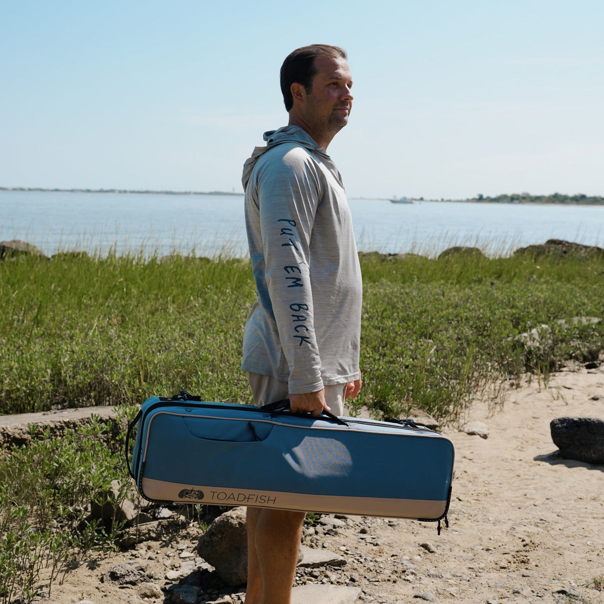 Angler carrying the Toadfish Fishing Travel Case by its handles along the coast